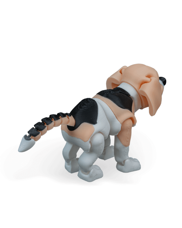 Zabawka Fafik Beagle z druku 3D widziana z tylnego prawego kąta. Ogon segmentowy w czarno-beżowych barwach unosi się ku górze. Widoczne są beżowe uszy, czarne łaty na grzbiecie oraz białe łapy i tylna część ciała.
