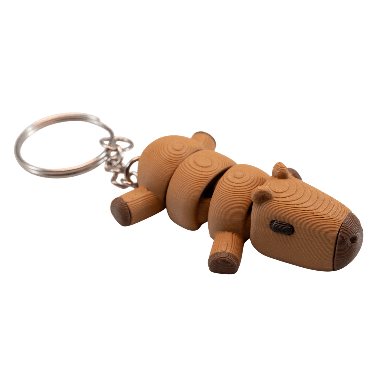 Kaprys - miniz brelok kapibara z druku 3D 2 Kaprys – brelok kapibara z druku 3D, widok z góry i z boku. Widoczna segmentowa budowa z koncentrycznymi okręgami na każdym segmencie. Beżowo-brązowy korpus z ciemniejszymi nóżkami i uszkami. Metalowe kółko do zawieszenia przy głowie.