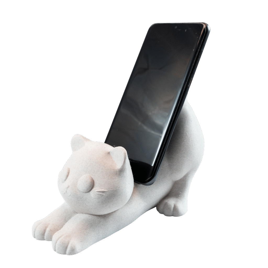 Koteł – uchwyt na telefon kot z druku 3D w białym kolorze, figurka kota trzymająca smartfon na biurku.