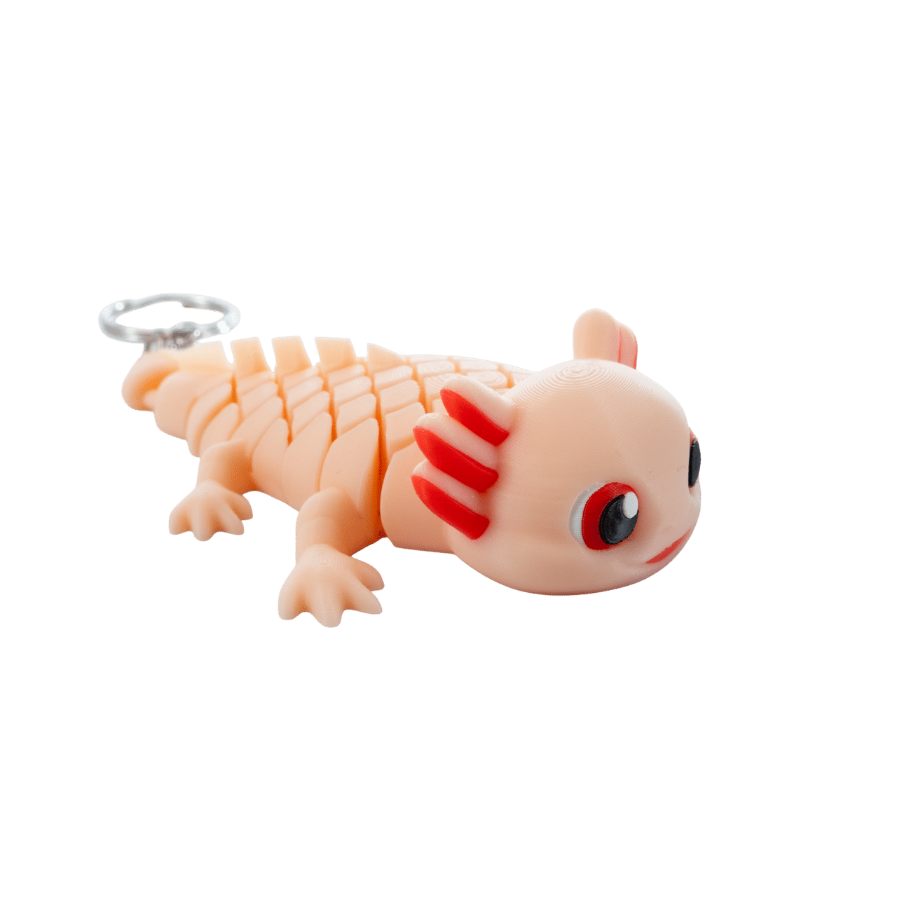 Saly – megaz brelok aksolotl z druku 3D 2 Saly – brelok aksolotl z druku 3D, widok z boku. Beżowo-pomarańczowy korpus z wyraźnie widocznymi czerwonymi paskami biegnącymi wzdłuż ciała. Czerwone skrzela na główce, duże oko z boku, delikatny uśmiech. Widoczne łapki i metalowe kółko do zawieszenia.