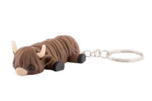 Futrzag – miniz brelok krowa highland z druku 3D - brązowa, włochata figurka w wersji mini z rogami i czarnymi kopytami, leżąca przy metalowym kółku do kluczy.