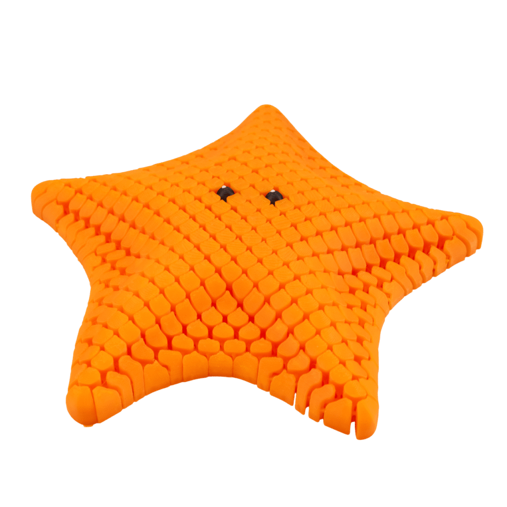 Gwiazdora – figurka rozgwiazda z druku 3D w kolorze pomarańczowym, o chropowatej fakturze i uśmiechniętym wyrazie.
