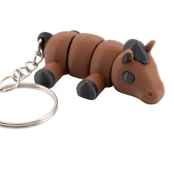 brelok koń z druku 3d w stylu miniz, mały brązowy konik o segmentowym ciele z czarną grzywą i kopytami, leżący przodem do obserwatora, z dużym metalowym kółkiem do kluczy po lewej stronie