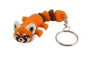 brelok panda ruda z druku 3d w wersji miniz, w żywym pomarańczowym kolorze, z kremowo-białymi uszami i policzkami oraz brązowymi akcentami na pyszczku; model leży w pozycji przodem do obiektywu, z dużymi, błyszczącymi oczami w stylu kawaii, okrągłą głową i segmentowanym ciałem składającym się z kilku ruchomych części; na końcu breloka znajduje się metalowy łańcuszek i kółko do kluczy; całość ma miękki, uroczy charakter typowej pandy rudej