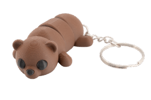 brelok miś z druku 3d w kolorze ciepłego brązu, przedstawiający leżącego misia o segmentowym, ruchomym korpusie; ma okrągłą głowę z małymi uszami, czarne oczy z delikatną teksturą warstw druku i mały czarny nosek, a z tyłu przymocowany jest metalowy łańcuszek z kółkiem do kluczy