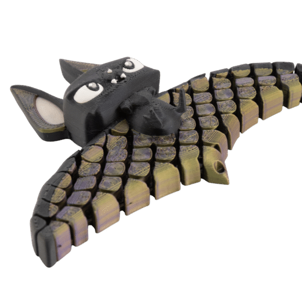 brelok nietoperz z druku 3d w kolorach czerni oraz przechodzącej fioletowo-złotej barwy na segmentowych skrzydłach, z dużymi białymi oczami i zwartą główką o wyrazistej, zabawnej mimice